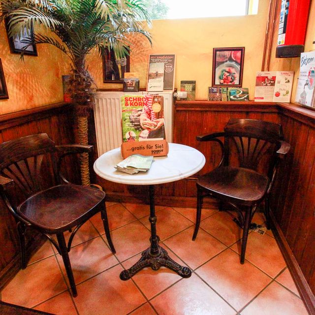 Bistrotisch mit zwei Holzstühlen vor holzvertäfelter Wand im Naturkostladen Häcklingen